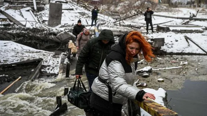 Civilians cross a river on a blown up bridge on Kyiv�s northern front on March 1, 2022. - Defending capital Kyiv, the "key priority" Ukrainian president said. (Photo by ARIS MESSINIS / AFP)
