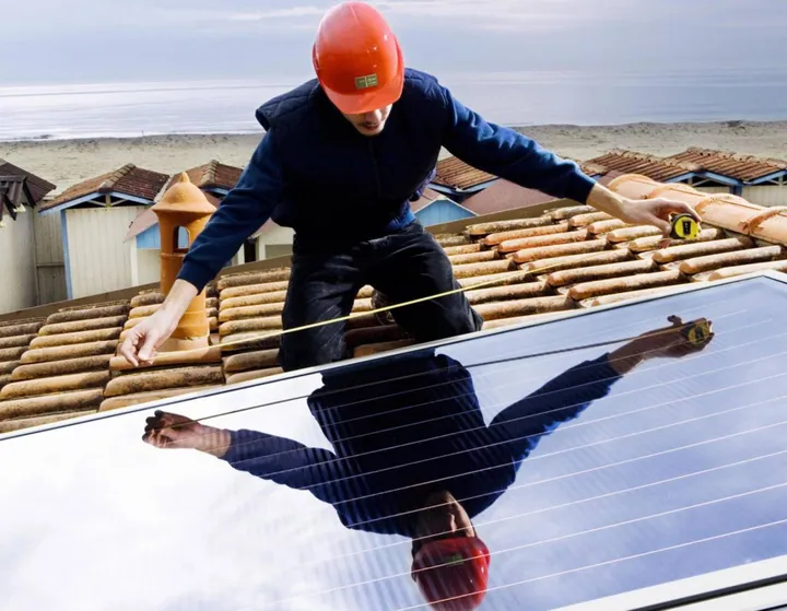 Un addetto al lavoro su un tetto per installare un impianto fotovoltaico (foto d’archivio)