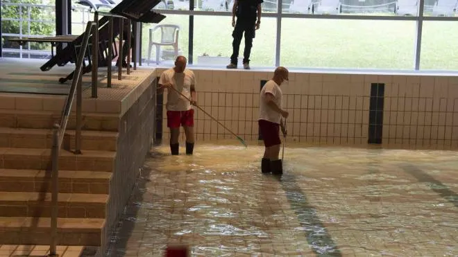 Gli operatori dello stabilimento termale di Porretta impegnati nelle pulizie della grande piscina sporcata di vernice
