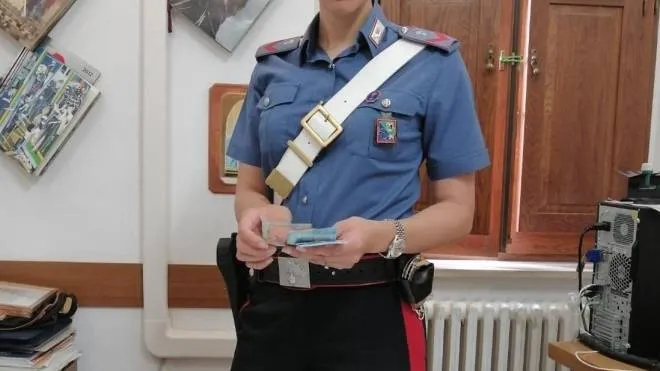 Una carabiniere mostra la droga, i contanti, i cellulari e il bilancino di precisione trovati in casa della giovane