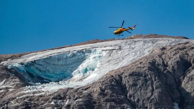 A rescue helicopter flies on July 4, 2022 over the glacier that collapsed the day before on the mountain of Marmolada, the highest in the Dolomites, one day after a record-high temperature of 10 degrees Celsius (50 degrees Fahrenheit) was recorded at the glacier's summit. - Rescuers resumed the search for survivors today after an avalanche set off by the collapse of the glacier, the largest in the Italian Alps, killed at least six people and injured eight others. (Photo by Pierre TEYSSOT / AFP)