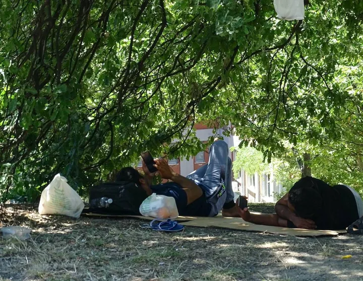 I migranti accampati l’altro giorno su dei cartoni all’ombra degli alberi davanti alla questura