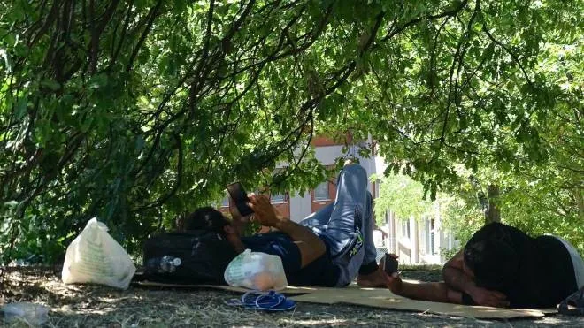 I migranti accampati l’altro giorno su dei cartoni all’ombra degli alberi davanti alla questura