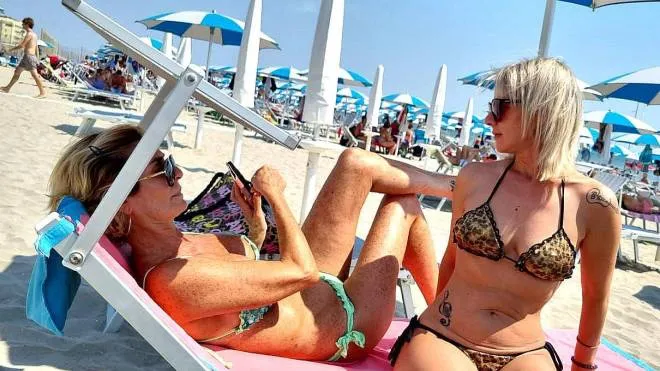 Due turiste sulla spiaggia dei Lidi si godono il sole dei giorni scorsi in uno dei tanti stabilimenti balneari
