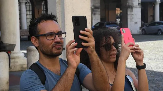 Due turisti in piazza Grande fotografano l’abside del Duomo