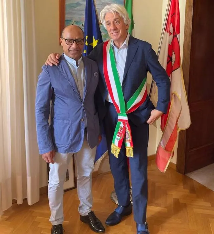 Il corriere Mhammed Diani con il sindaco Sandro Parcaroli per la consegna della cittadinanza italiana. In piccolo la pagina del Carlino dello scorso gennaio