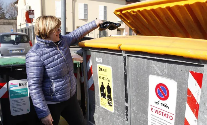 Una donna conferisce i rifiuti nel bidone della plastica (repertorio)