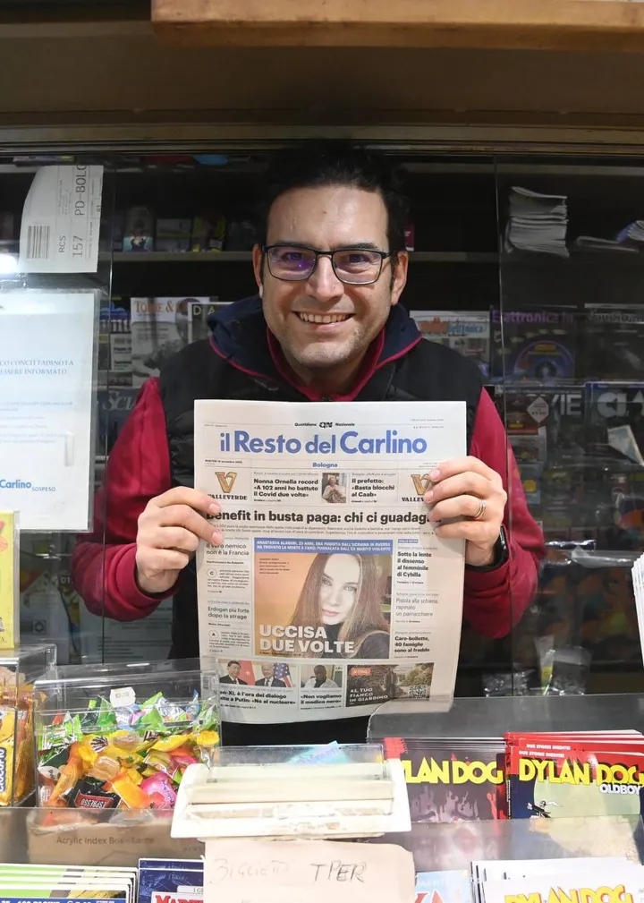 Un edicolante mostra una copia del Carlino: anche domani i giornalai saranno al lavoro
