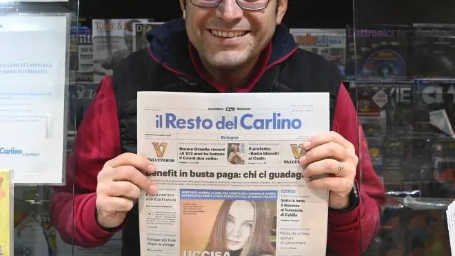 Un edicolante mostra una copia del Carlino: anche domani i giornalai saranno al lavoro