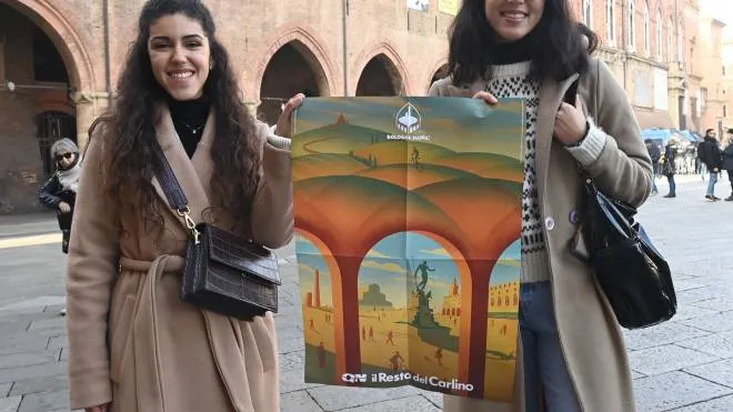 Due ragazze col poster che mostra le due anime di Bologna: paesaggistica e storica