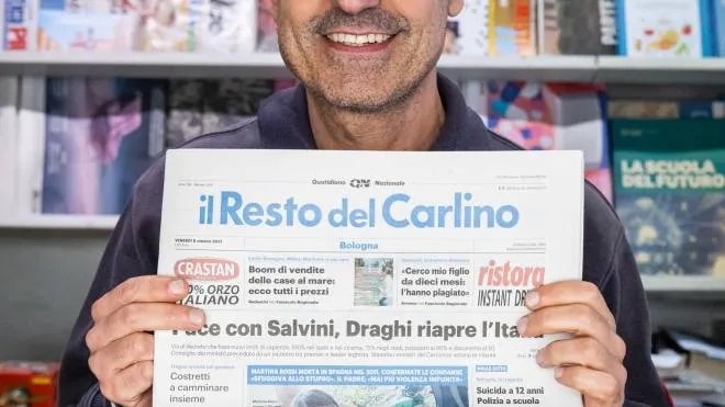 Un edicolante mostra una copia del Carlino: ecco dove comprare il giornale domani