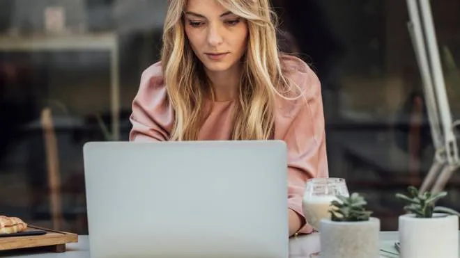 Pretty elegant Caucasian woman sitting at cafe and typing on laptop.donna al computer